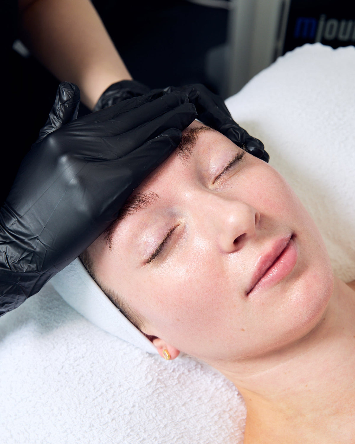 Esthetician gently massaging a client's face during a calming facial for sensitive skin at Sapien Skin + Beauty
